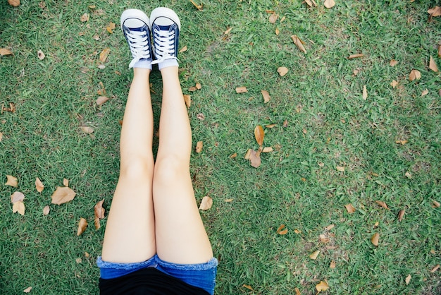 woman feet in gumshoes on green grass in the park 