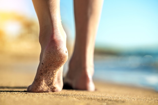 woman feet walking barefoot on sand leaving footprints