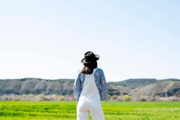 Woman in the field with black hat on her back