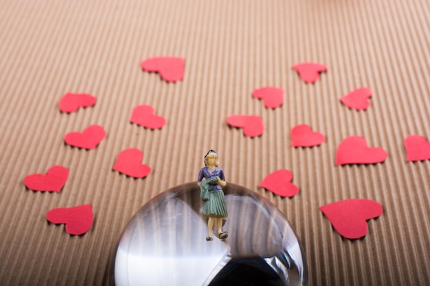 Woman figurine on half a globe with paper hearts