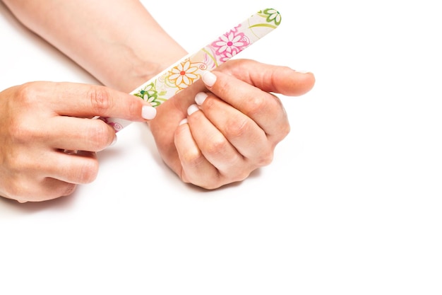 Woman filing her nails with a colored file on a white background with copy space