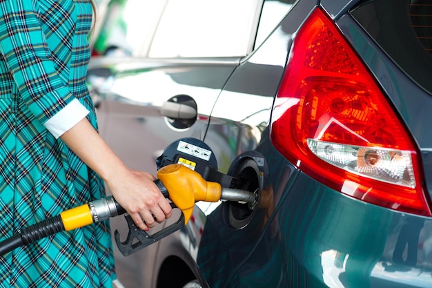 Photo woman fills petrol into the car at a gas station