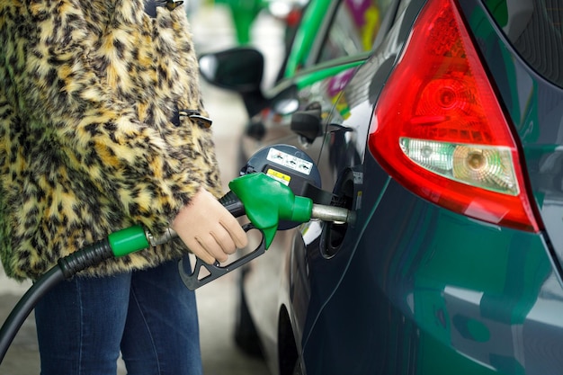 Photo woman fills petrol into her car at a gas station in winter