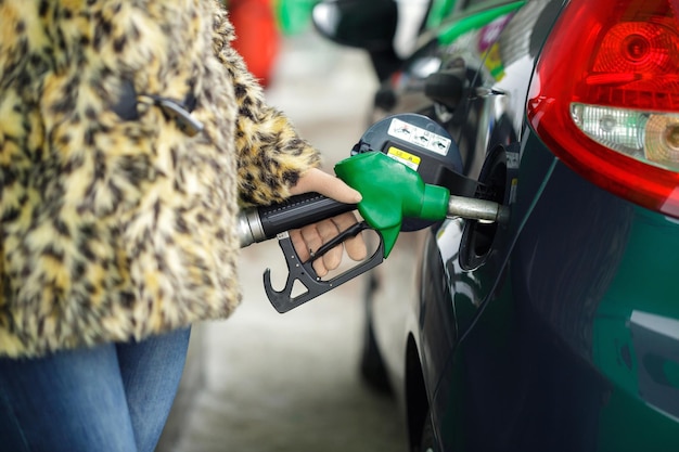 Photo woman fills petrol into her car at a gas station in winter