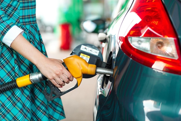 Photo woman fills petrol into her car at a gas station