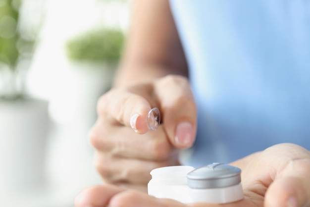 Woman finger pulling out contact lens from plastic container closeup correction of myopia