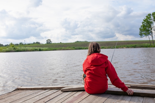 Woman Fisherman sits with her back to the viewer and holds a fishing rod in her hand Woman catching a fish
Girl fishing