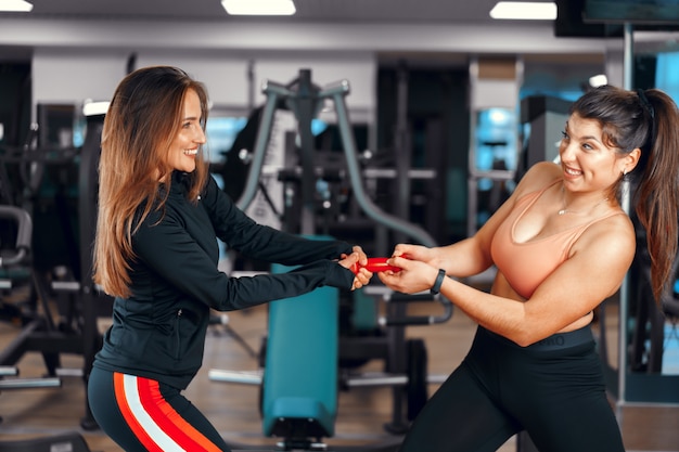 Woman fitness trainer and her client in a gym