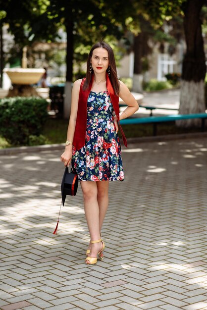 Photo a woman in a floral dress is walking on a sidewalk