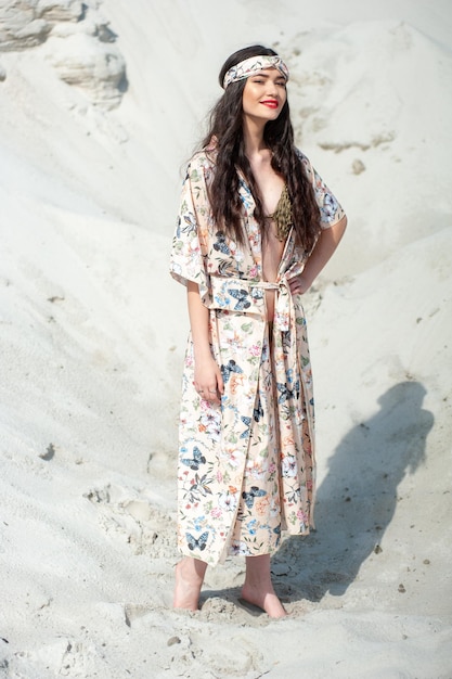 A woman in a floral dress stands on the beach.