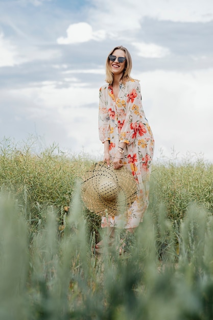 Woman in a floral dress with a woven hat in a field