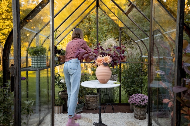 Photo woman florist makes a beautiful bouquet in glasshouse at back yard