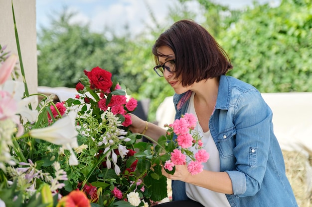 Woman florist making flower arrangement in basket outdoor