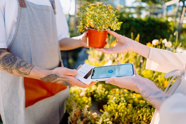 Woman in florist shop is paying with smartphone money transaction mobile payment high quality photo