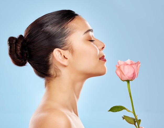 Photo woman flower and beauty in studio or skincare smooth and sustainable cosmetics on blue background female person rose plant and organic facial treatment dermatology and eco friendly in profile