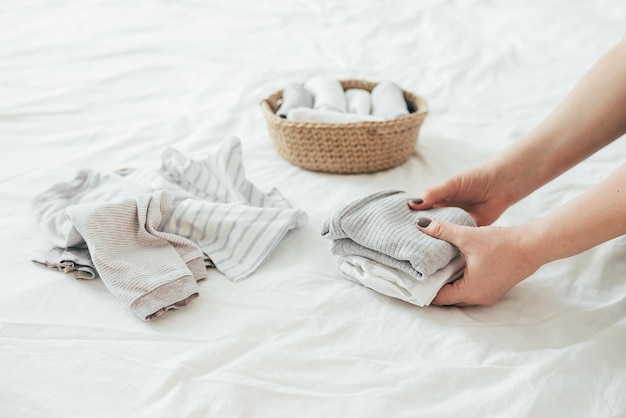 Woman folding clothes in jute basket in the konmari system Concept of organizing minimalism clothes