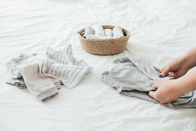 Woman folding clothes in jute basket in the konmari system Concept of organizing minimalism clothes