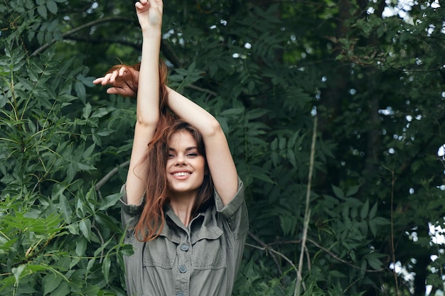 Woman in the forest holds his hands above his head green leaves