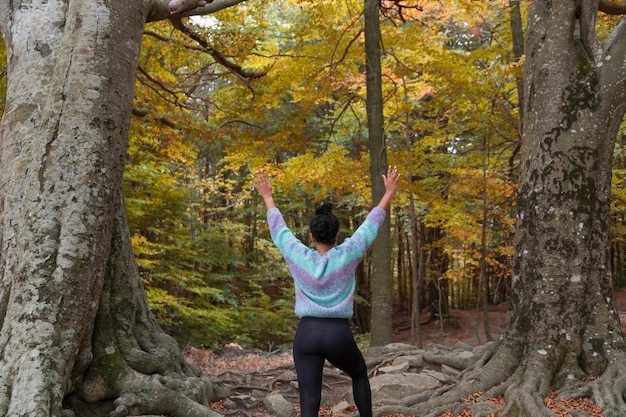 A woman in a forest with her arms up in the air