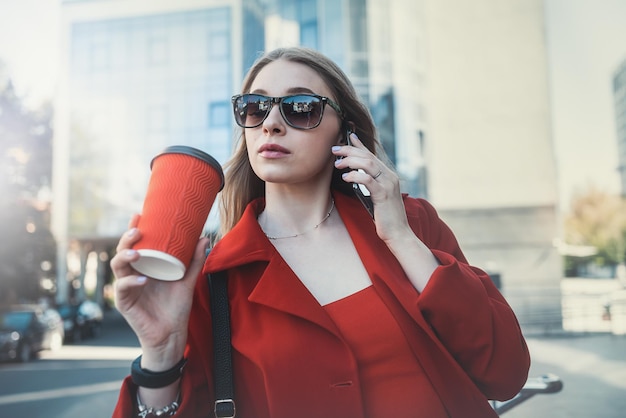 Woman in formal suit enjoying sunny day and walking near the skyscrapers during