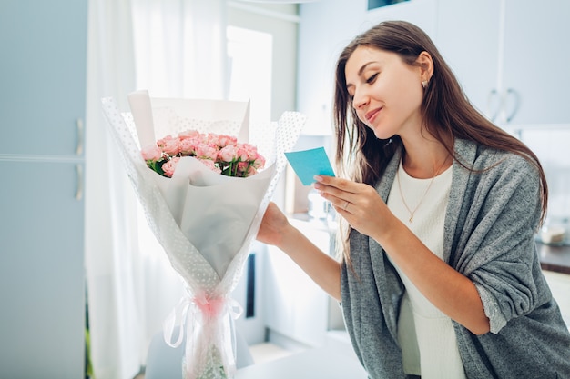 Woman found bouquet of flowers on kitchen and reading card on kitchen. Surprise. Present for holiday