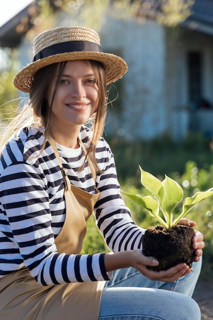 Woman gardener holding plant in hands in garden