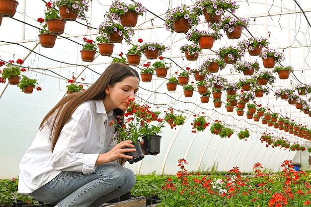 Woman gardener sniffing flower against large flower plantations People job and lifestyle concept