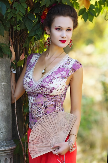 Woman in geisha makeup holding fan in her hands 