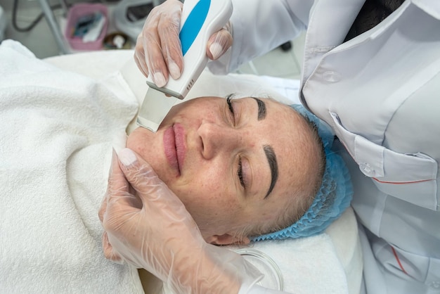 Woman gets her skin cleaned of blackheads and other impurities with the help of a spatula