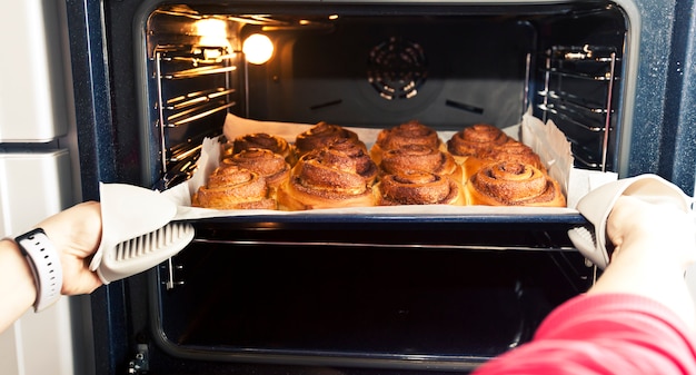 Woman gets out the deco with the fresh bakery from the oven