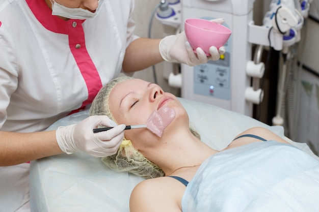 Woman getting face peeling mask in spa beauty salon