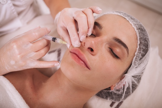 Woman getting filler injections at beauty clinic