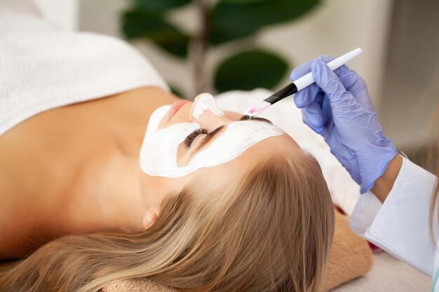 Woman getting spa face mask in beauty studio