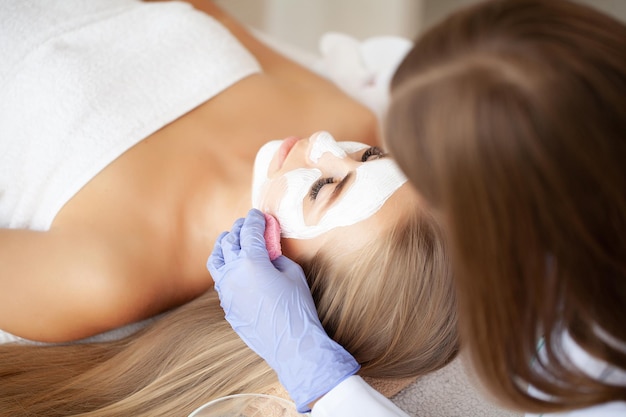 Woman getting spa face mask in beauty studio