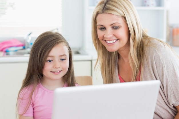 Woman and girl looking at the laptop monitor 