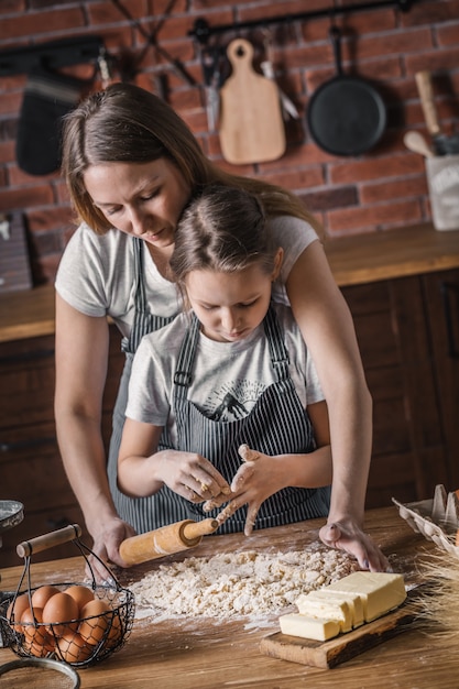 Woman and girl preparing dough with pin