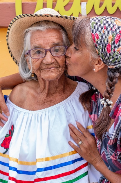 Woman gives a tender kiss on the cheek to her 95 year old mother Portrait of mother and daughter