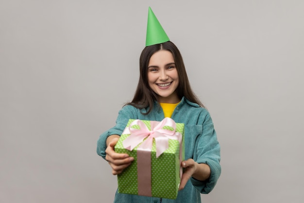 Woman giving green gift to camera and smiling sharing holiday present congratulating on birthday