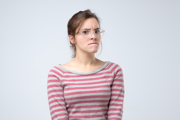 Woman in glasses looks aside with pensive expression