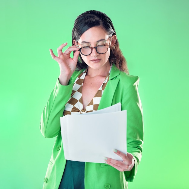 Woman in glasses reading paper isolated on green background for fashion design career gen z resume and internship Young person or model with retro clothes and documents review for job opportunity