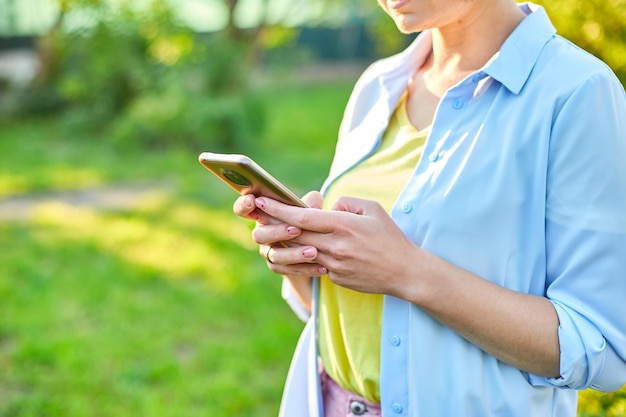 Woman in glasses using smartphone type messages on mobile phone