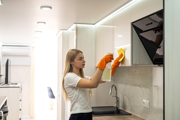 Woman in glove with spray cleaning a surface of her kitchen