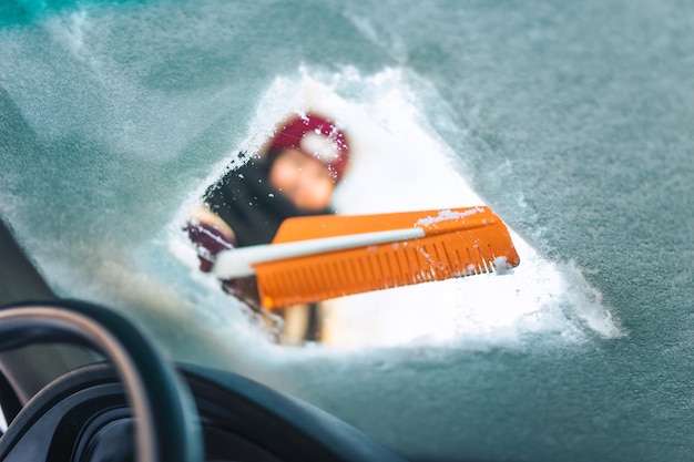 Woman in gloves removes snow from the car