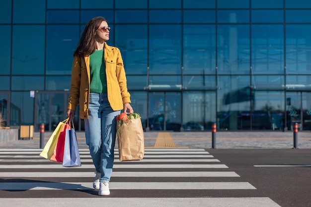 Woman go crosswalk from a shopping mall with shopping bags with a groceries