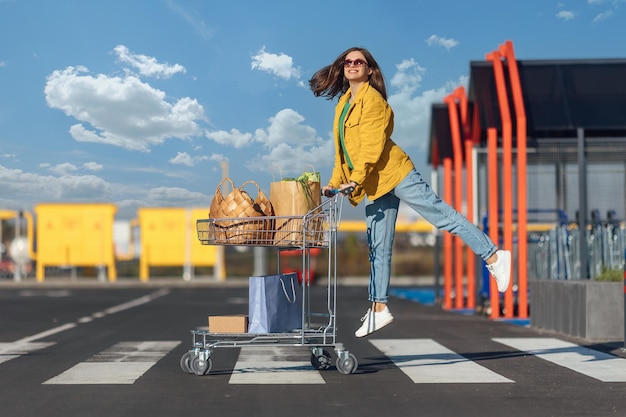 Woman goes crosswalk from a shopping mall with shopping cart with a groceries