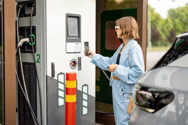 Woman going to charge electric car on public power station