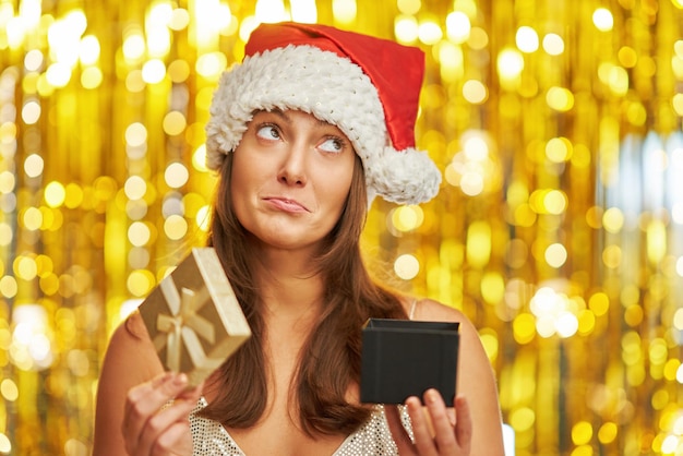 Woman over gold background in Santa Claus hat