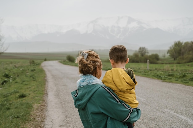 woman grandmother and her grandson travel along a road with a view of the mountains