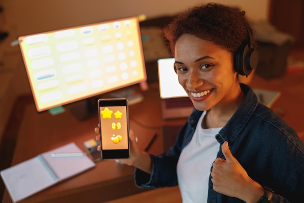 Woman graphic designer is showing smartphone during work day in home office