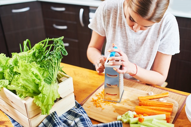 Woman grates the carrots in the kitchen